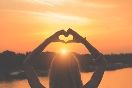 Heart signal over the sunset with human hands.