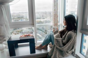 Girl wrapped in a blanket looking out the window