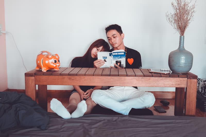couple-reading-book-sitting-on-front-of-rectangular-brown-table