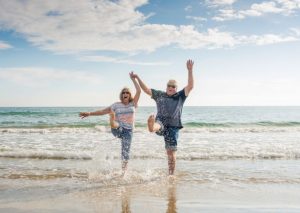 A couple kicking water at the ocean shore.