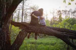 People arm round each other on a tree.